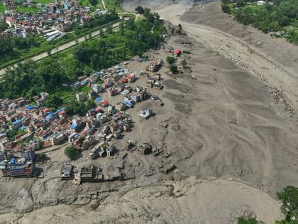 Damaged houses stand precariously near the swollen, debris-choked banks of the Trishuli River after flash floods in Nepal’s Nuwakot district yesterday.