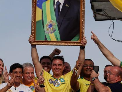 Opposition presidential candidate Flavio Bolsonaro holds a photo of his father, former President Jair Bolsonaro, as he rides a boat during a campaign rally ahead of the October general election in Angra dos Reis, Rio de Janeiro state, Brazil, Saturday.