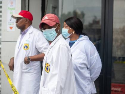 
Forensic officials stand outside a party hall in the aftermath of a fire that broke out in the building hosting a wedding party in Lingwala, Congo, Saturday.