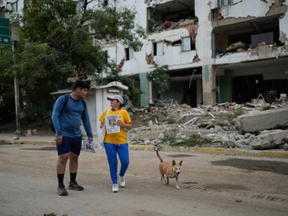 Pedro Gomez, left, walks through La Guaira, Venezuela, with a friend, asking people if they have seen his cousin, Andres Molina, who has been missing since the earthquakes, Saturday, August 22, 2026. (AP Photo/Ariana Cubillos) 