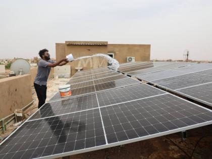 A technician cleans solar panels installed on the roof of a home in Omdurman, on the outskirts of Khartoum, Sudan.