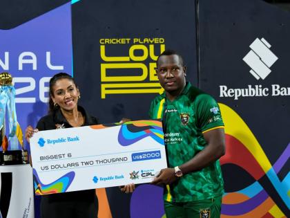 Jamaica Kingsmen Captain Rovman Powell (right) collects a cheque for hitting the biggest six after losing to the Antigua and Barbuda Falcons in this year’s Republic Bank Caribbean Premier League final at Kensington Oval on Sunday. 