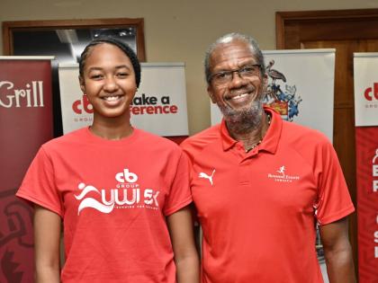 Quacian Stewart (left), recipient of the Franno Claudia Francis Carnigan Scholarship, stands beside UWI 5K organiser, Alfred ‘Franno’ Francis, during last Thursday’s launch at the school grounds. 