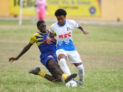 HIllel Academy’s Christian Foster (right) comes under a crunching challenge from St Mary’s College’s Dellano Nelson during their ISSA Manning Cup game at the Hillel playfield yesterday.
