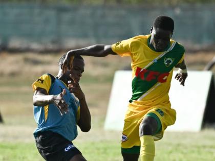 Kingston Technical High School’s Richard West (left) tries to get close to Excelsior High School’s Aldeano Walters during their Walker Cup football encounter at Excelsior High’s playing field on September 26.