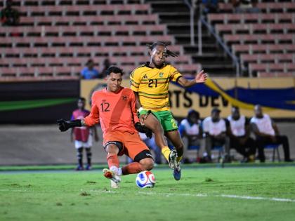 Jamaica’s Rumarn Burrell (right) puts the ball past Guatemala’s goalkeeper Kenderson Navarro during their Concacaf Nations League match at the National Stadium on Friday night. Jamaica won 3-2. 