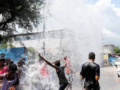 In this file photo, residents of Bundy Lane in St Andrew play in water from a burst underground National Water Commission pipe.