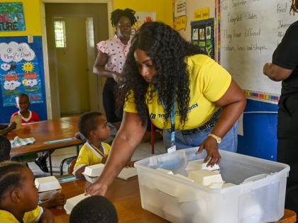 Theresa Garnett, of the Transport Authority of Jamaica’s Customer Service Department, serves breakfast to students at Dalvey Infant School on September 25. 