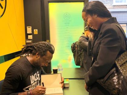 Marlon James signs his Booker Prize shortlisted book The Disappearers for a visitor at the book signing event at the Jamaica Patty Company restaurant.
