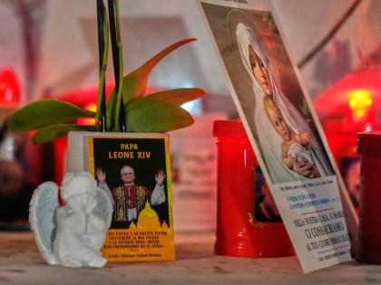 An image of Pope Leo XIV rests at the base of a statue of the late Pope John Paul II outside the Agostino Gemelli Polyclinic, where Leo is hospitalized for surgery to remove a lung nodule, in Rome, Tuesday, Oct. 13, 2026. 