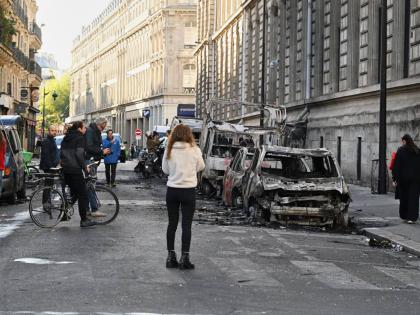 People look at charred cars the day after a demonstration against rising living costs, joining students’ grievances, in Paris. 