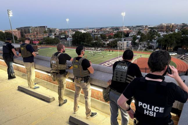 Officers from Metropolitan Police Department, FBI, and Homeland Security Investigations (HSI) are seen monitoring a football game between Bell Multicultural and Archbishop Carroll on September 12, at Cardozo High School in the Columbia Heights neighbourhoo