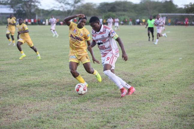 Glenmuir’s Orane Watson goes on a dribble while being chased by Garvey Maceo’s Ajani Johnson during their ISSA daCosta Cup football match at the Garvey Maceo playfield yesterday.