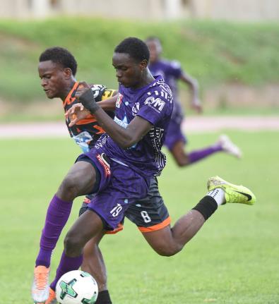 Kingston College’s Deshawn Byfield (right) turns away from Tivoli’s Malachi Rose during their ISSA/WATA Manning Cup clash at the Stadium East field yesterday. KC won the game 4-0.