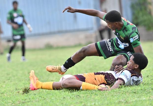 Calabar’s Kimani Thompson is felled by a cruching challenge from Wolmer’s Boys’ School’s D’Andre Campbell during their ISS/WATA Manning Cup Zone E playoff clash at the Mico University yesterday.