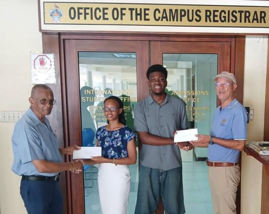 Radley Reid (left) and Donald Patterson (right), directors of the Rotary Club of St Andrew North Education Foundation, present education grants to Lilly Anne Douglas and Victor Stewart of The University of the West Indies. The recipients were two of four s