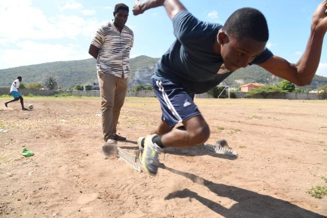 Track and field coach Carl Page (left) helps one of his charges, Jhadon Burke, manage his starts during a training session at the Bridgeport High School in 2023.