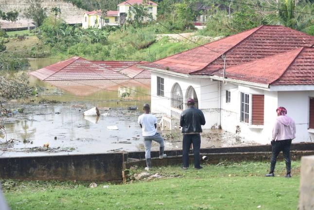 Onlookers view houses and motor vehicles that were left submerged on Gibson Close in Mandeville, Manchester, after the passage of Hurricane Melissa.