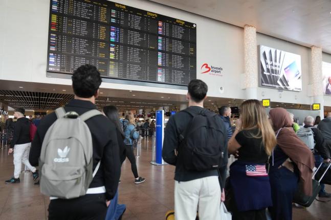 Passengers look at a departure board after several cancellations and delays as a result of reported overnight drone activity over Brussels International Airport in Zaventem.