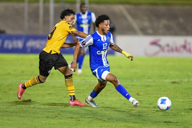 Mount Pleasant’s Kimoni Bailey makes a pass ahead of the chasing Anyelo Gomez of Universidad O&M during the Concacaf Caribbean Cup final at the National Stadium in Kingston last night. Jamaica drew the seond-leg game 2-2 after a 1-0 win in the Dominican 