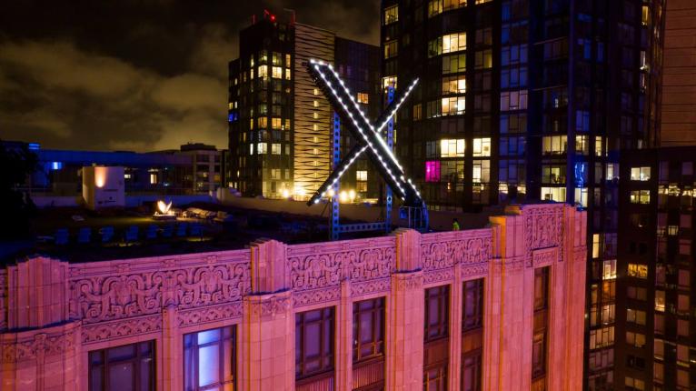 FILE - Workers install lighting on an "X" sign atop the company headquarters in downtown San Francisco on July 28, 2023.