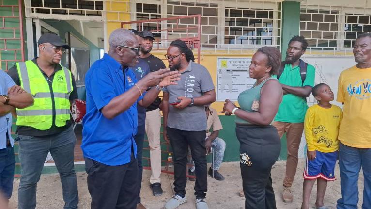 Desmond McKenzie (second left), minister of local government and community development, addresses a concerned resident at the Petersfield High School shelter yesterday, following a break-in at the facility. 