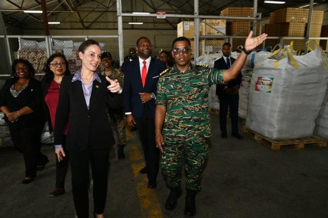 Minister of Foreign Affairs and Foreign Trade, Senator Kamina Johnson Smith (left), looks on as Colonel General Staff, Guyana Defence Force, Captain Vernon Burnette, points out hurricane relief items donated by Guyana, including roofing material for the re