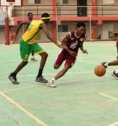 Herbert Morrison Technical High School’s Ryan Jurdine (right) dribbles by Ocho Rios High School’s Michael Rubie during their ISSA Schoolboy Basketball match at the Herbert Morrison court on Monday.