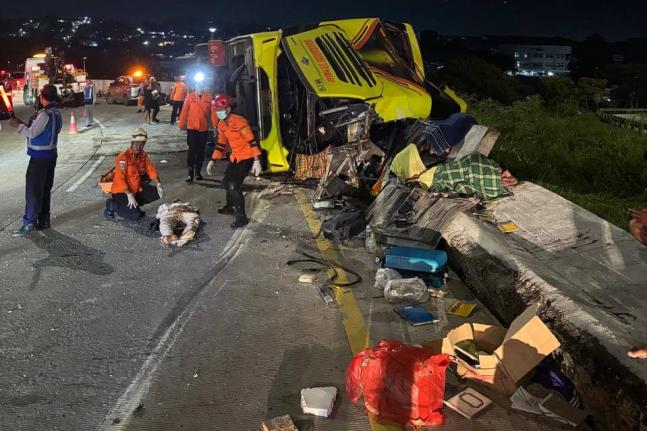 In this photo released by the Semarang Search and Rescue Office, rescuers tend to a victim of a deadly bus crash on a toll road in Semarang, Central Java, Indonesia, Monday, December 22, 2025. (Semarang SAR Office via AP)