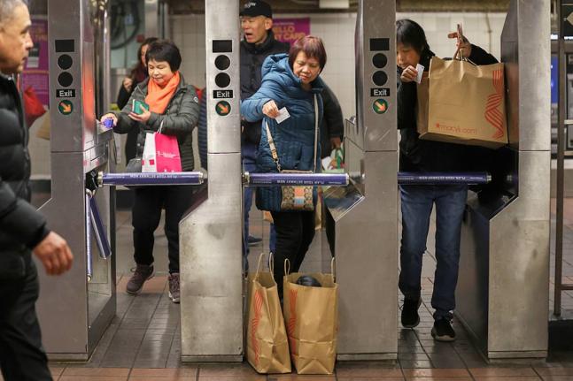 Shoppers swipe their MetroCards as they enter the subway turnstiles, in November 2024, in New York. 