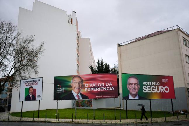 A person walks past presidential election campaign billboards for candidates André Ventura of Chega party, Luís Marques Mendes from Social Democratic Party and António José Seguro of Socialist Party, in Lisbon.