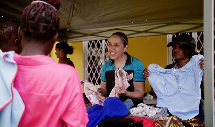 Intcomex Jamaica executives Claudia Bermudez-Rodriguez (left), sales manager, and Cecile Cameron, operations manager, assist residents during the company’s Christmas outreach in Cave district. Families enjoyed a “no-pay shopping” event, choosing clot