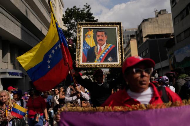 A government supporter holds an image of President Nicolás Maduro during a women’s march to demand his return in Caracas, Venezuela.