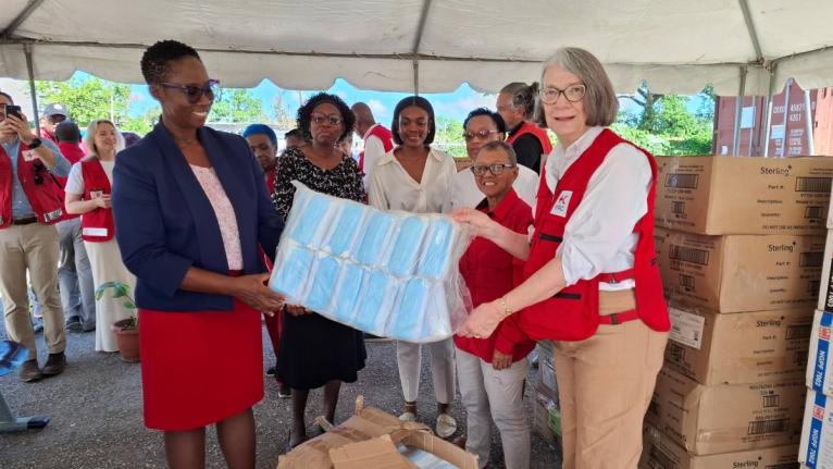 Novlin Leslie Little (left), parish manager for the Westmoreland Public Health Services; and  Kate Forbes (right), president, International Federation of Red Cross and Red Crescent Societies, display donated flu supplies while looking on are (from second l