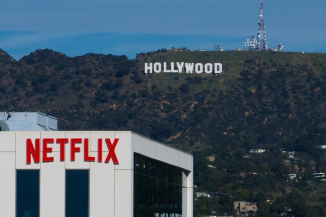 A Netflix sign is displayed atop a building in Los Angeles, on December 18, 2025, with the Hollywood sign in the distance. (AP Photo/Jae C. Hong, File)