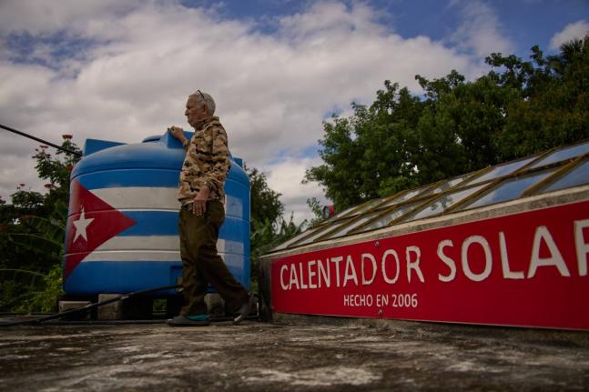 Felix Jose Morfi stands by his solar-powered water heater system he set up on his home’s roof in Regla, Havana province, Cuba, on January 29.