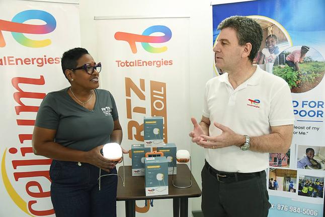 Marsha Burrell Rose (left), marketing and public relations manager, Food For The Poor, Jamaica, gets a feel of the Sunshine 150 Solar Lamp, 1,164 of which were donated by TotalEnergies Jamaica’s managing director, Vincent Daniault, assisting the charity 