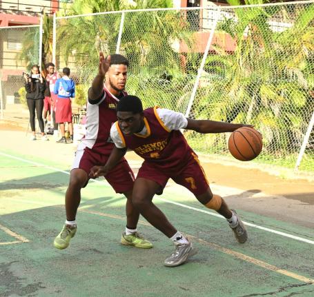 Holmwood Technical High School’s Nickoy Knight (right) tries to dribbles by Herbert Morrison Technical High School’s Joshua Ferguson during their ISSA Schoolboy Under-19 Basketball quarterfinal match at Herbert Morrison court yesterday.