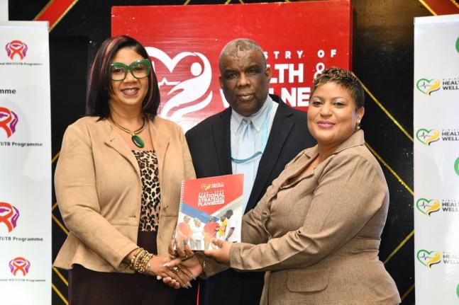 Minister of State in the Ministry of Health and Wellness, Krystal Lee (right), presents a copy of the National Strategic Plan for HIV 2023-2030, to Deputy Coordinator for the Caribbean Regional Programme, United States Embassy in Jamaica, Ava-Gay Timberlak