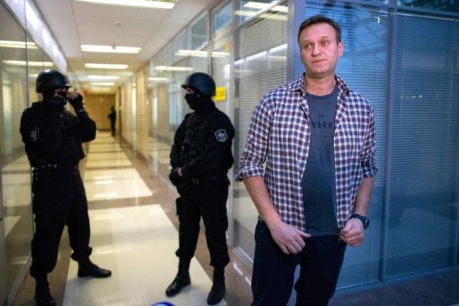Former Russian opposition leader Alexei Navalny speaks to the media in front of security officers standing guard at the Foundation for Fighting Corruption office in Moscow, Russia on December 26, 2019.