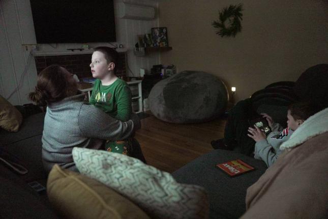 Ronan Murphy snuggles with his mom, Andrea, while looking at the snow falling outside his home while brother, Connor sits nearby in Ayer, Massachusetts, USA, on January 17, 2026. 