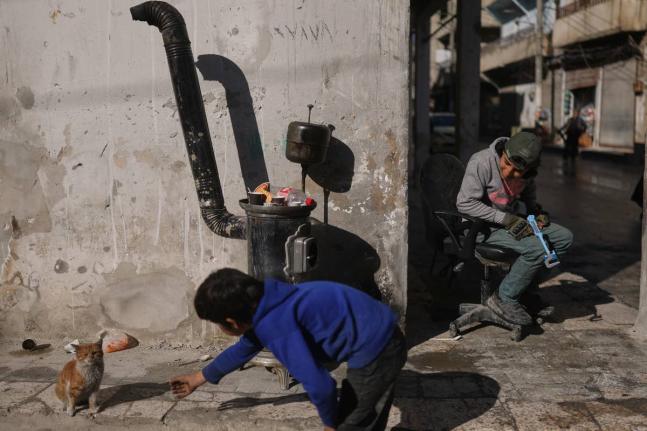 A boy plays with a cat on a street of the Kurdish-majority neighbourhood of Sheikh Maqsoud, in Aleppo, Syria.