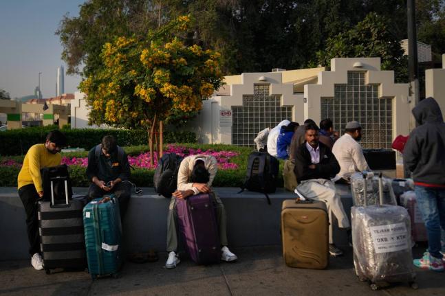 Passengers stranded by the closure of Dubai International Airport await for assistance in the airport parking lot in Dubai, United Arab Emirates on Sunday.