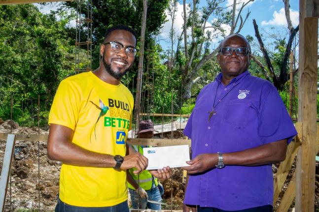 Omar Wright (left), lead, environment and community development at the JN Foundation presents a cheque to Reverend Father Garvin Augustine, executive director of Mustard Seed Communities to carry out repairs to Blessed Assurance in St James, which was dama