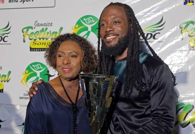 Minister of Culture, Gender, Entertainment and Sport, Olivia Grange (left), presents 2026 Jamaica Festival Song Competition winner dBurnz with his trophy, at the grand finale of the competition held at the Ranny Williams Entertainment Centre in St Andrew o