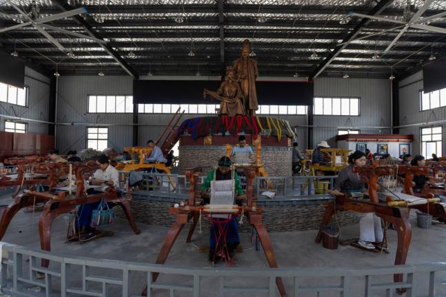 Workers weave Pulu, a traditional wooden fabric into clothing, at wooden looms near statues of Princess Wencheng and Tibetan King Songtsen Gampo at the Ethnic Huaji Handwoven Cooperative in Shannan in western China’s Tibet Autonomous Region.