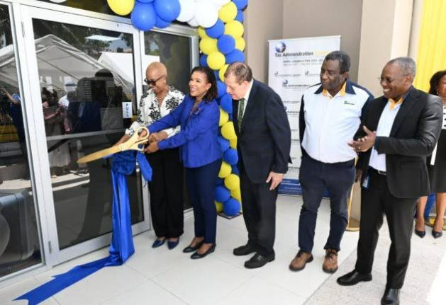 Minister of Finance and the Public Service, Fayval Williams (fifth right), and Minister without Portfolio in the Office of the Prime Minister with responsibility for Efficiency, Innovation and Digital Transformation, Audrey Marks (fourth right) cut the rib