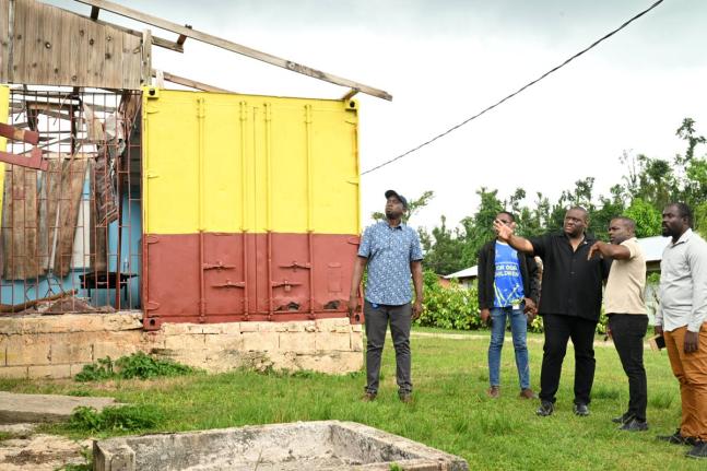 Parliamentary Secretary in the Ministry of Education, Skills, Youth and Information, Marlon Morgan (centre), and Principal of Maggotty High School, Sean Graham (second right), inspect a damaged structure on the school compound during a Back-to-School tour 