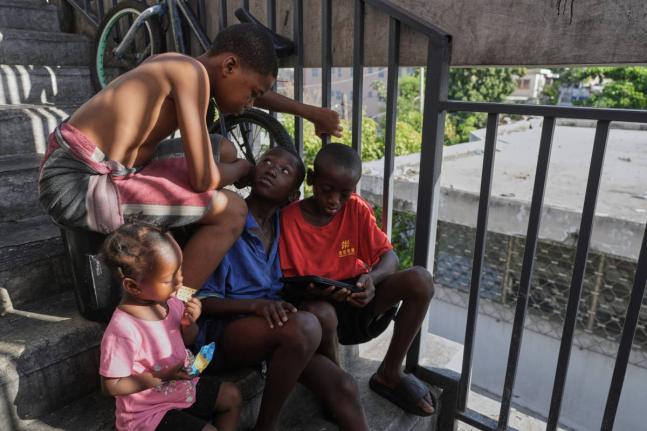 Children watch a movie on a mobile device at a shelter for families displaced by gang violence in Port-au-Prince, Haiti, Wednesday.