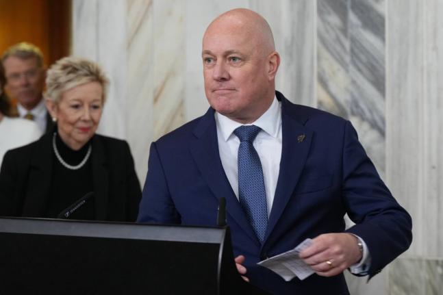 New Zealand Prime Minister Christopher Luxon speaks to reporters at Parliament in Wellington, New Zealand, on Wednesday, Aug. 12 2026, after surviving a leadership vote among his own party’s lawmakers. (AP Photo/Charlotte Graham-McLay) CORRECTION: Correc